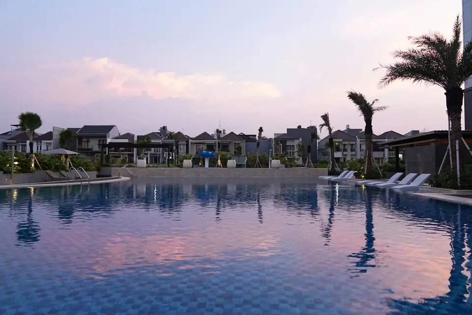 Kolam renang resort saat senja dengan pantulan langit